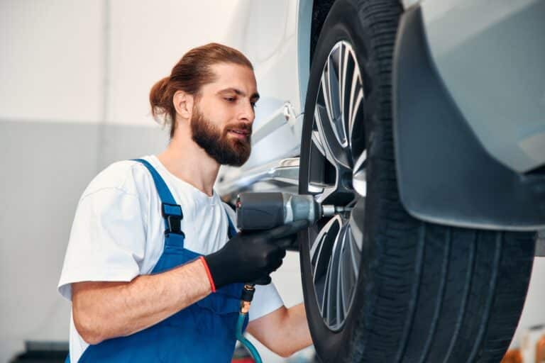 Mécanicien ajustant les roues d'une voiture de luxe.