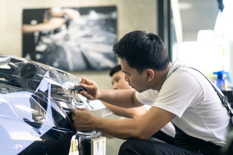 Techniciens installant un film de protection sur la carrosserie d'une voiture.